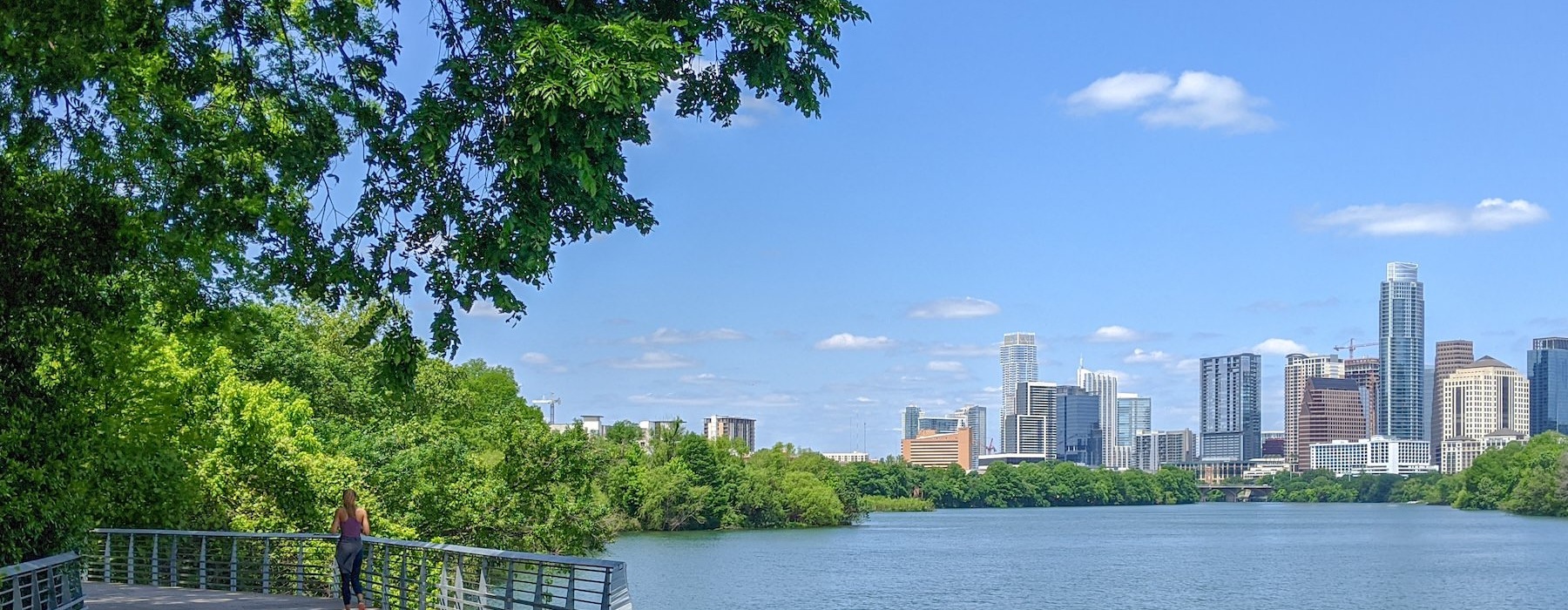a person standing on a bridge over a body of water with a city in the background